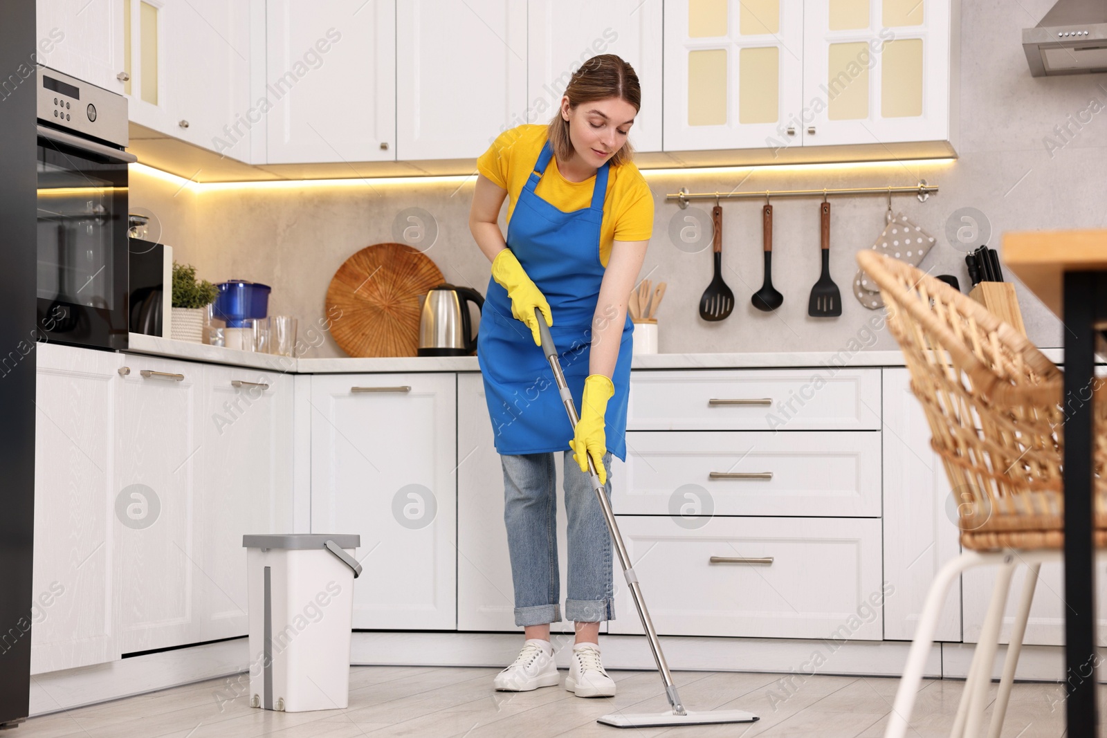 Photo of Cleaning service worker washing floor with mop in kitchen