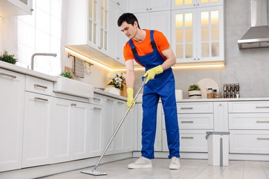 Photo of Cleaning service worker washing floor with mop in kitchen