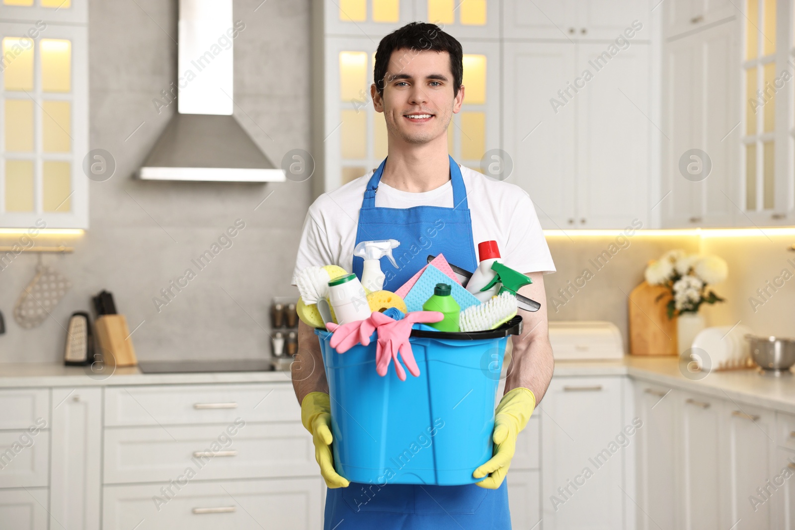 Photo of Cleaning service worker holding bucket with supplies in kitchen