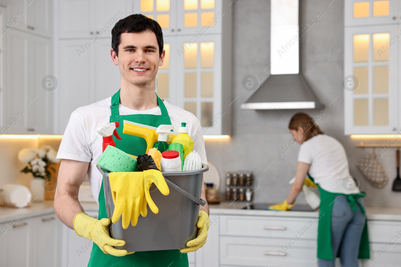 Photo of Cleaning service worker holding bucket with supplies in kitchen