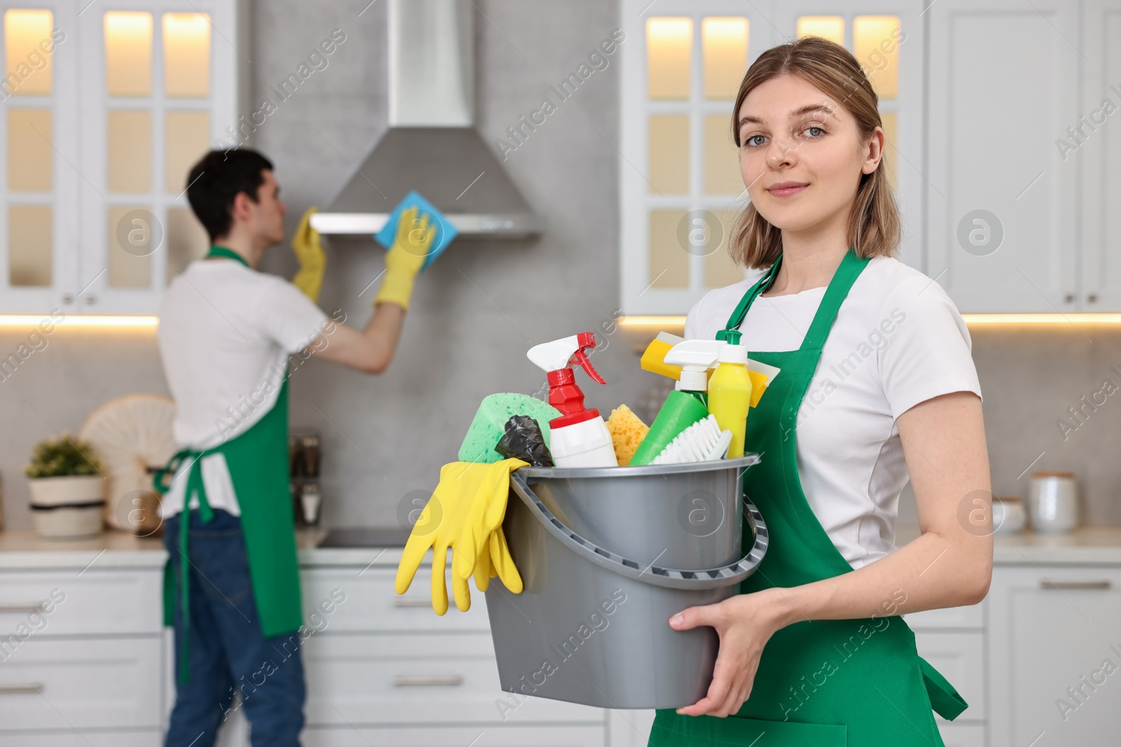 Photo of Cleaning service worker holding bucket with supplies in kitchen