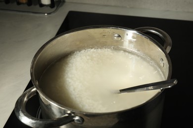 Photo of Boiled rice in pot on induction stove, closeup