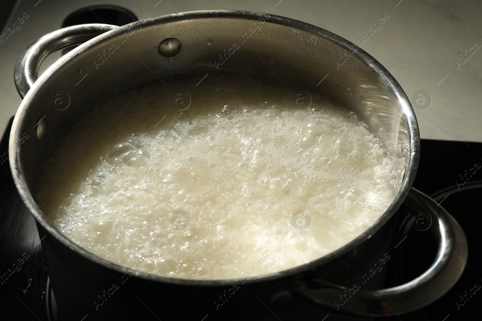 Photo of Boiling rice in metal pot on stove, closeup