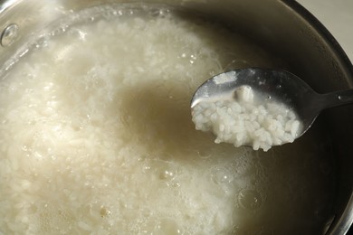 Photo of Boiled rice in spoon over metal pot