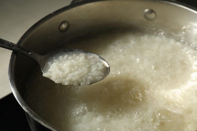 Photo of Boiled rice in spoon over metal pot