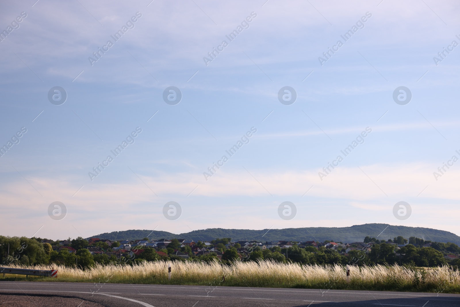 Photo of View of mountain, village and road under blue sky