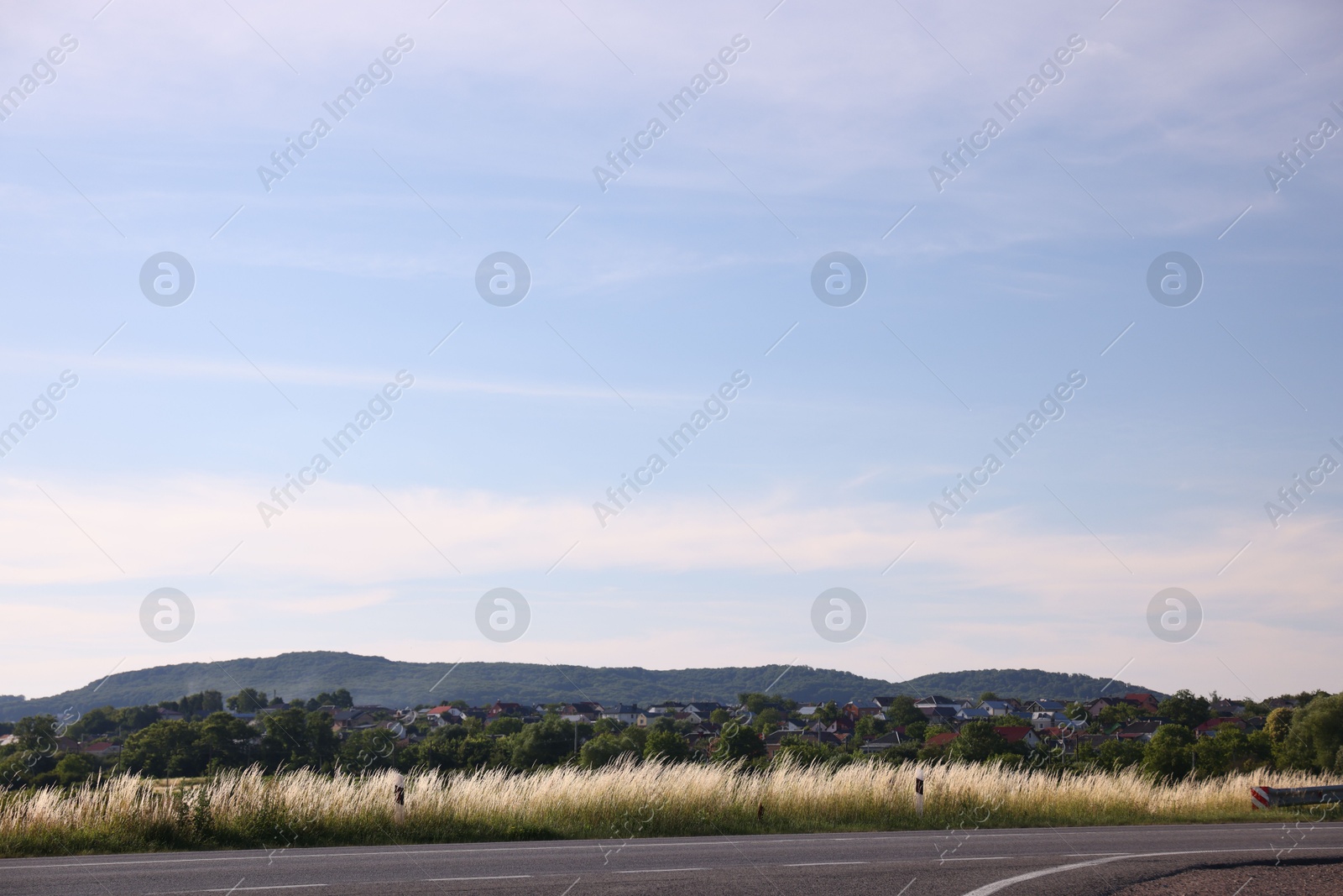 Photo of View of mountain, village and road under blue sky