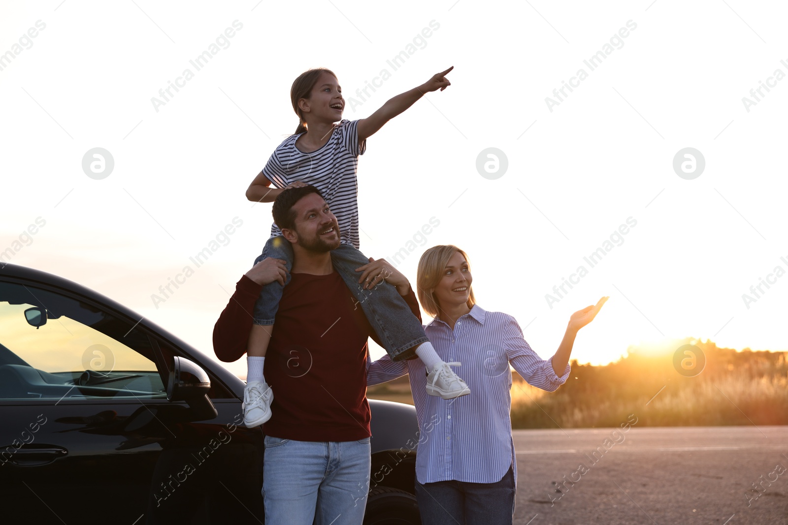 Photo of Cute family near car outdoors at sunset