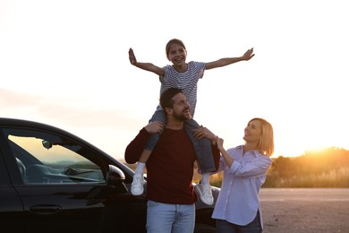 Photo of Cute family near car outdoors at sunset