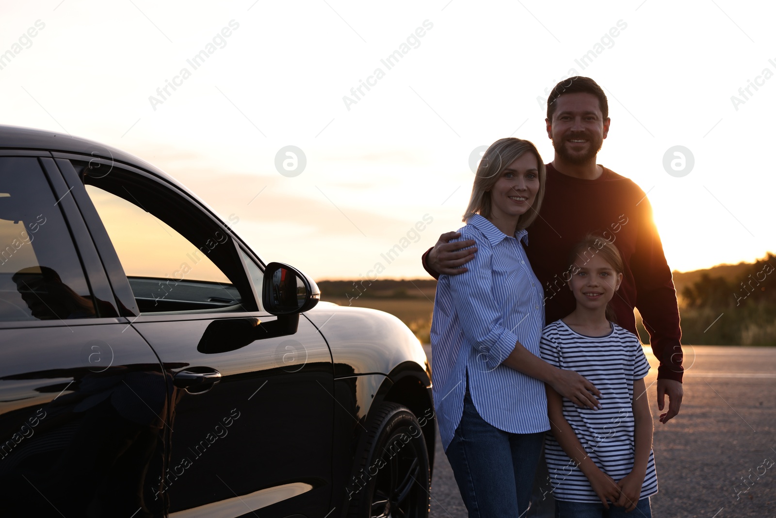 Photo of Cute family near car outdoors at sunset