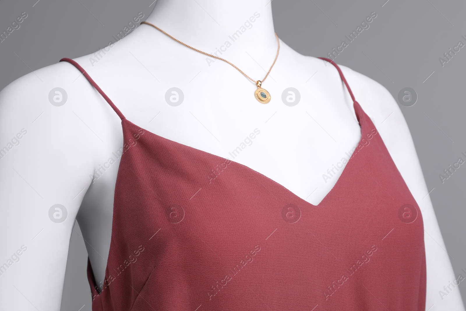 Photo of Female mannequin with necklace dressed in stylish red dress on grey background, closeup