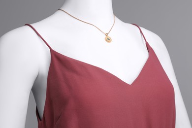 Photo of Female mannequin with necklace dressed in stylish red dress on grey background, closeup
