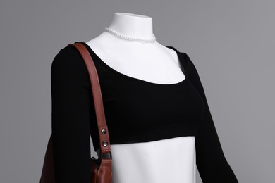 Photo of Female mannequin with necklace and bag dressed in stylish outfit on grey background