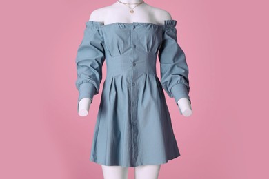 Photo of Female mannequin dressed in light blue dress with necklace on pink background. Stylish outfit
