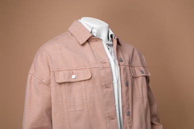 Male mannequin dressed in white shirt and jacket on beige background