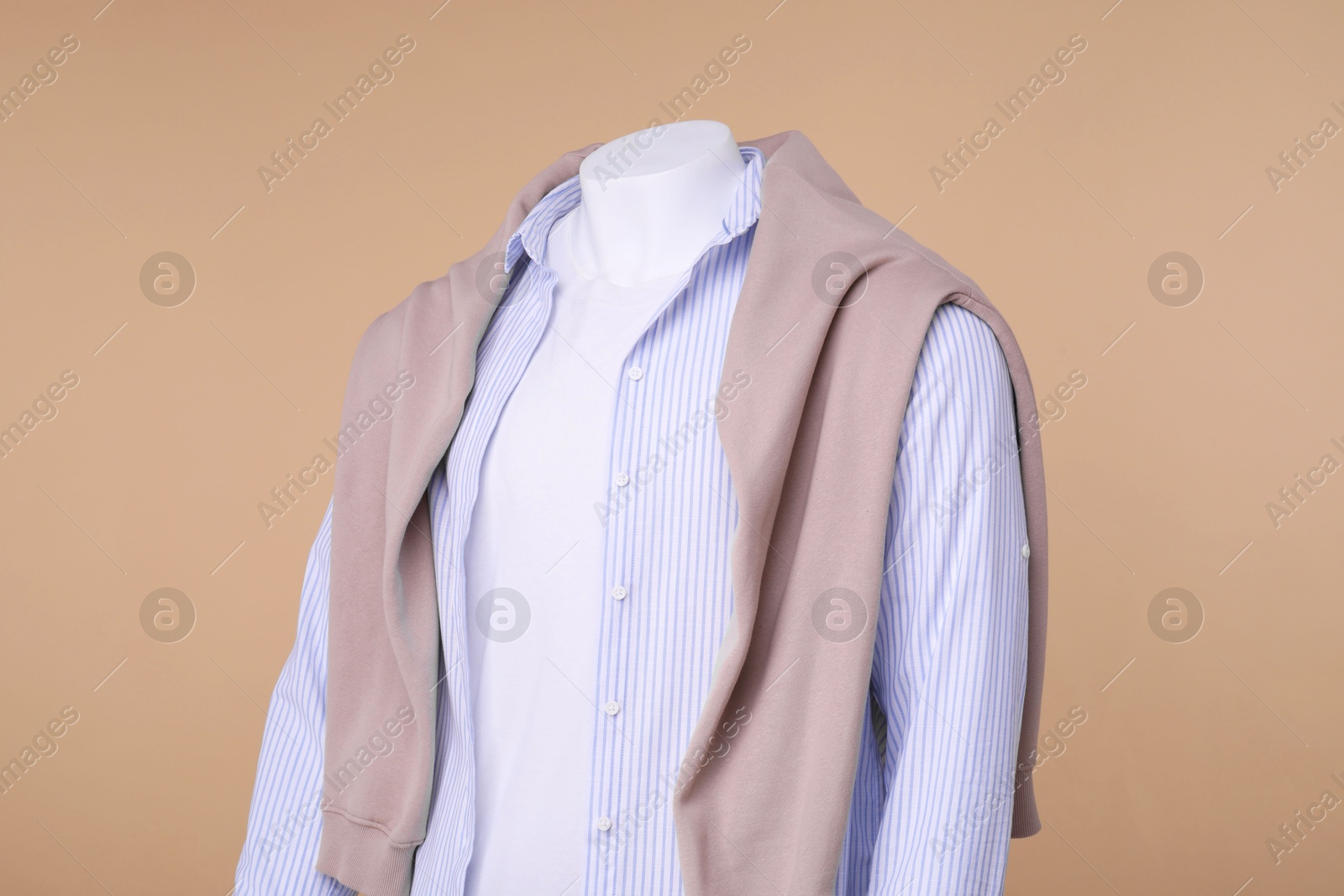 Photo of Male mannequin dressed in white t-shirt, sweater and striped shirt on beige background