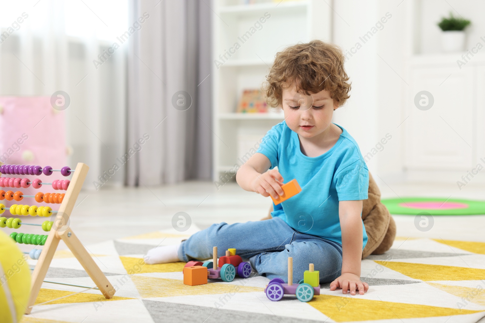 Photo of Cute little boy playing with toy cars on floor in kindergarten