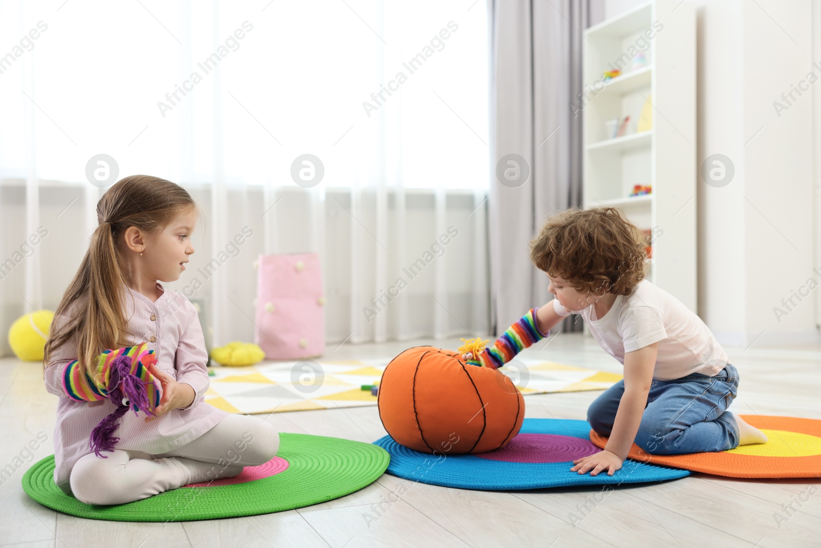 Photo of Cute little children playing with funny sock puppets and soft toy ball in kindergarten