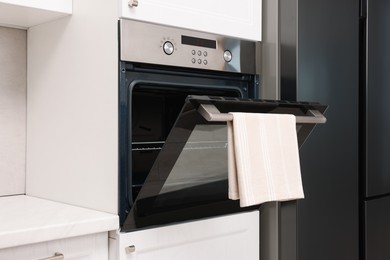 Photo of Open electric oven with towel in kitchen. Cooking appliance