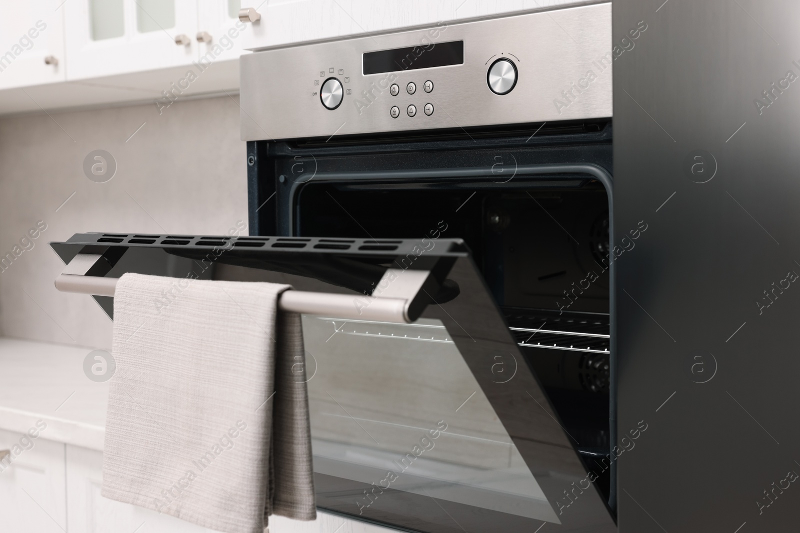 Photo of Open electric oven with towel in kitchen. Cooking appliance