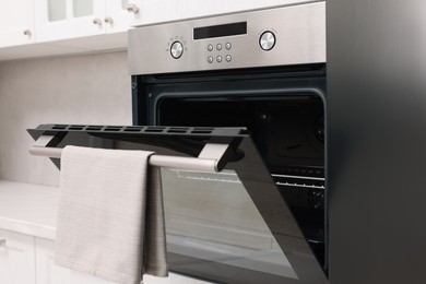 Open electric oven with towel in kitchen. Cooking appliance