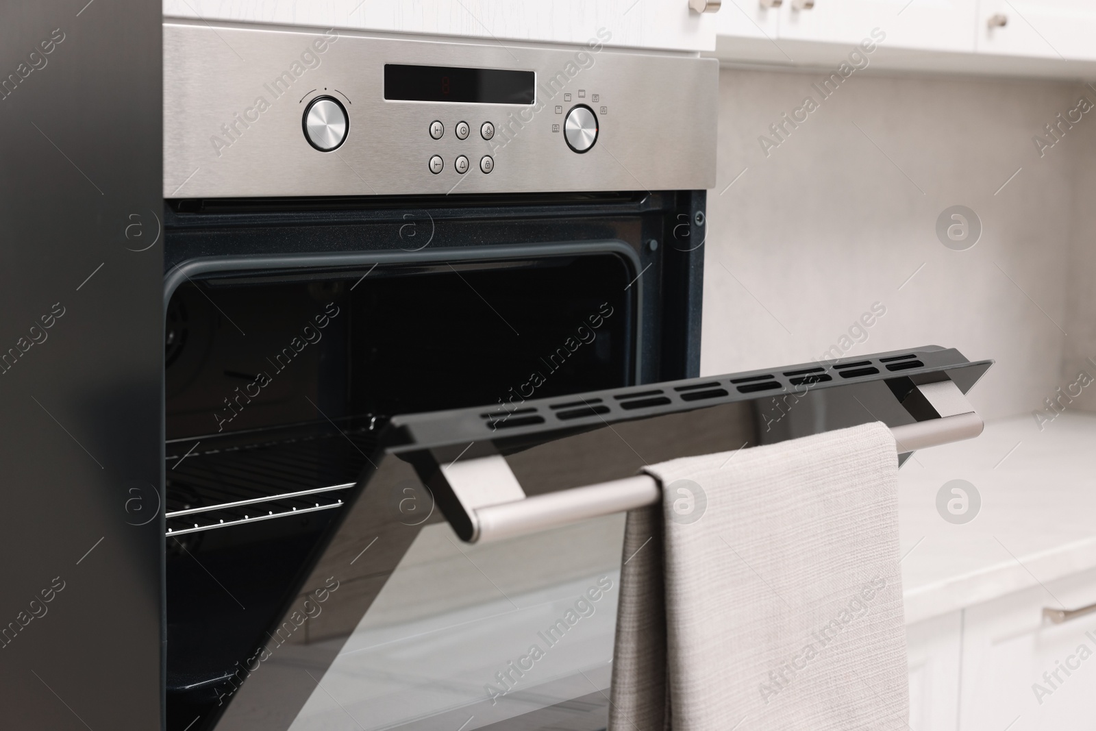 Photo of Open electric oven with towel in kitchen. Cooking appliance