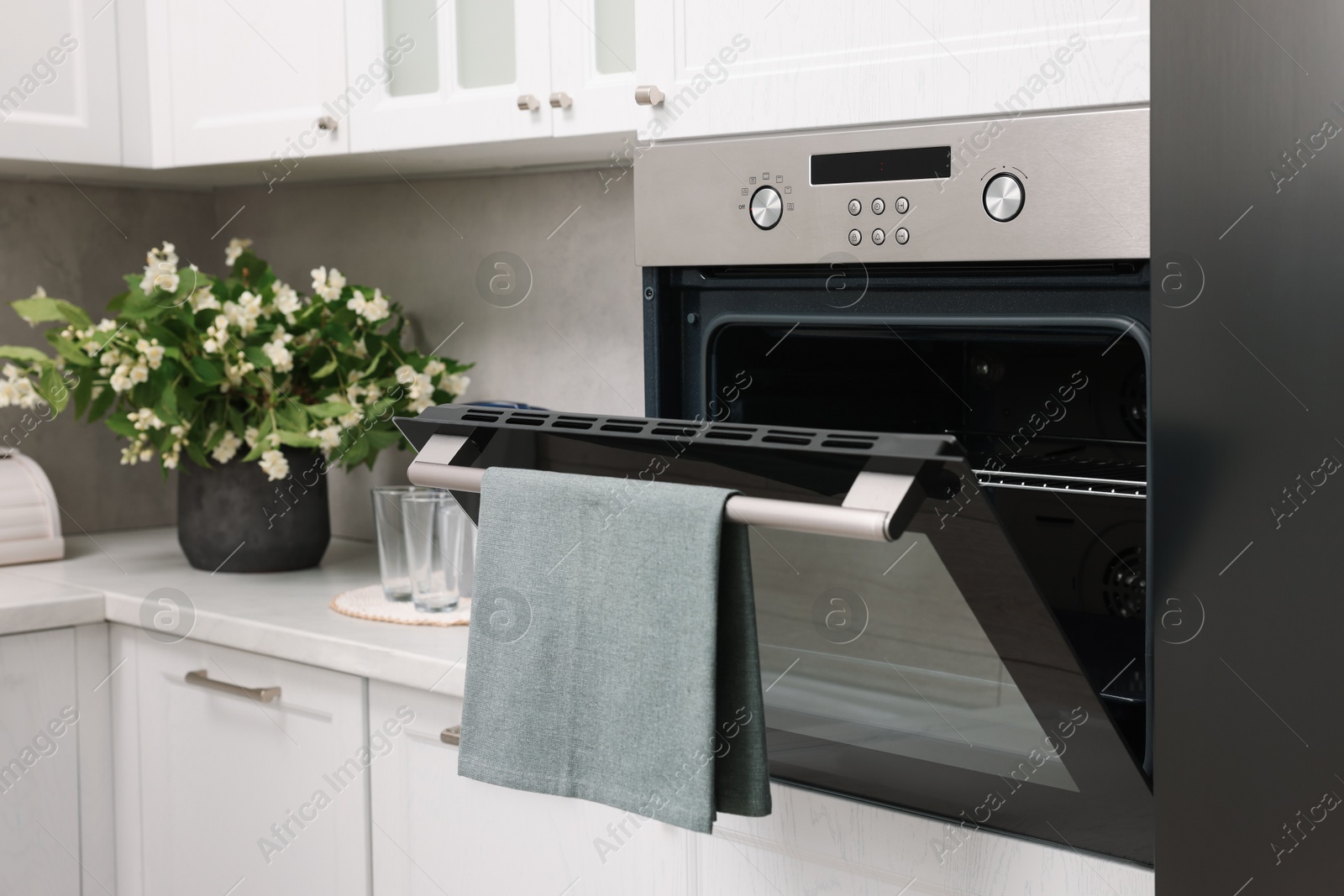 Photo of Open electric oven with towel in kitchen. Cooking appliance