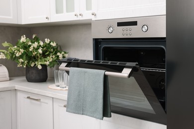 Open electric oven with towel in kitchen. Cooking appliance