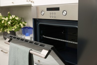 Photo of Open electric oven with towel in kitchen. Cooking appliance