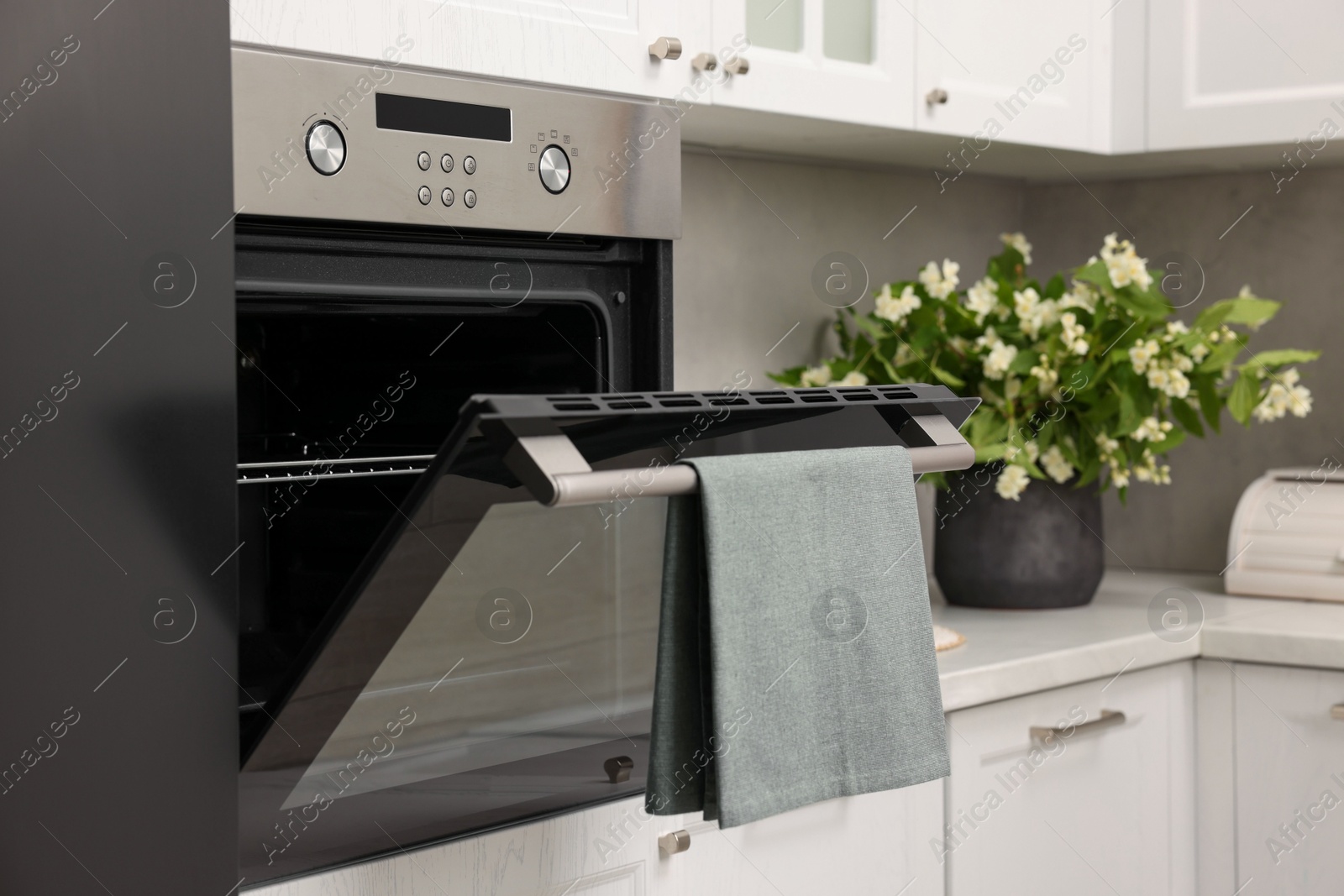 Photo of Open electric oven with towel in kitchen. Cooking appliance