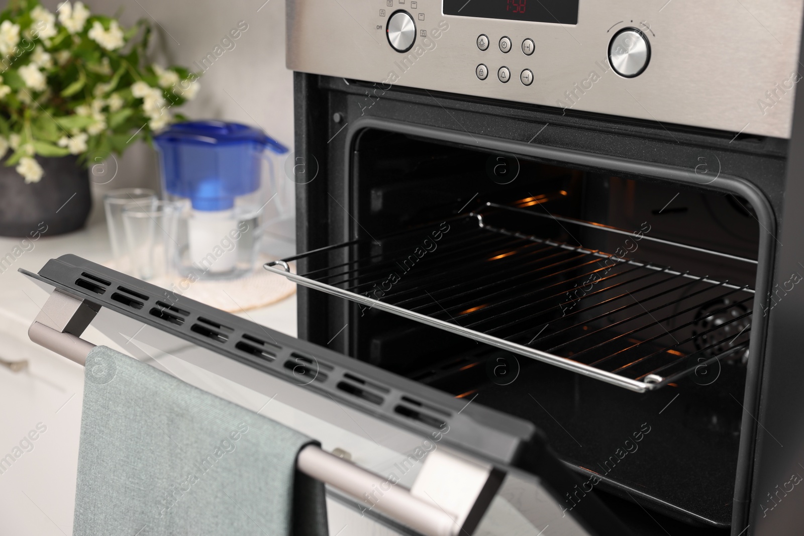 Photo of Open electric oven with towel in kitchen. Cooking appliance