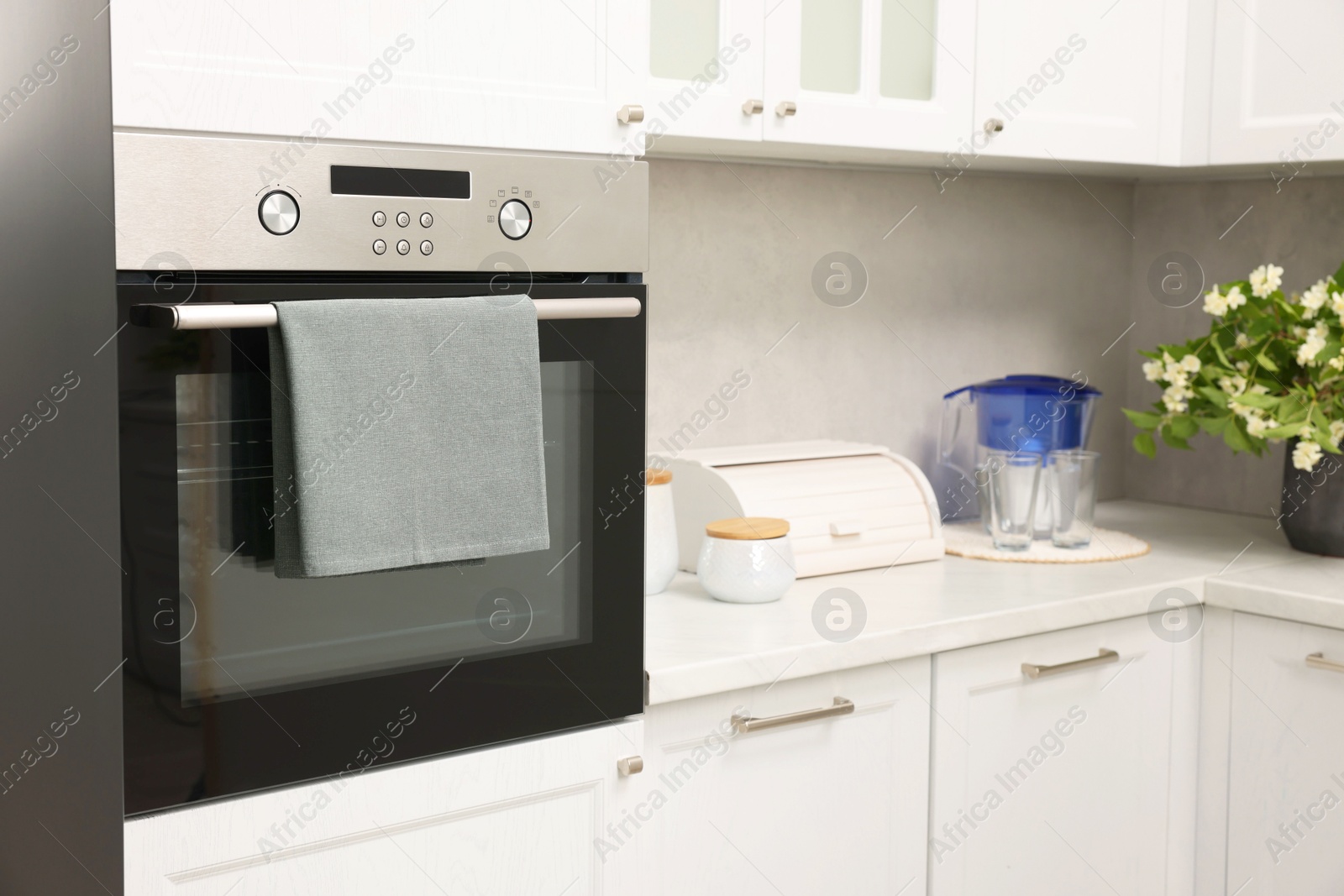 Photo of Electric oven with towel in kitchen. Cooking appliance