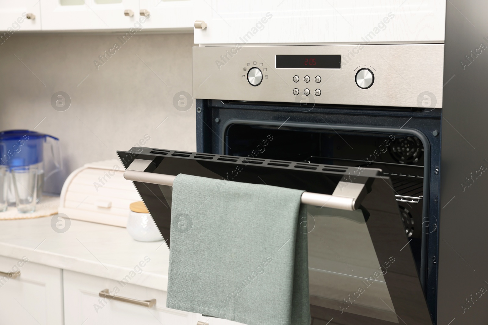 Photo of Open electric oven with towel in kitchen. Cooking appliance