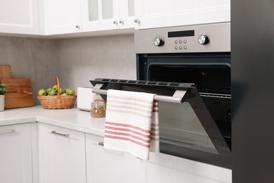 Photo of Open electric oven with towel in kitchen. Cooking appliance