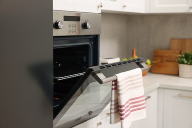 Photo of Open electric oven with towel in kitchen. Cooking appliance