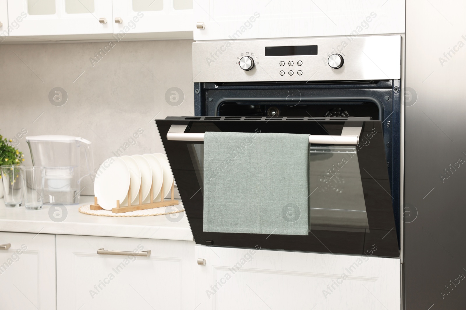 Photo of Open electric oven with towel in kitchen. Cooking appliance