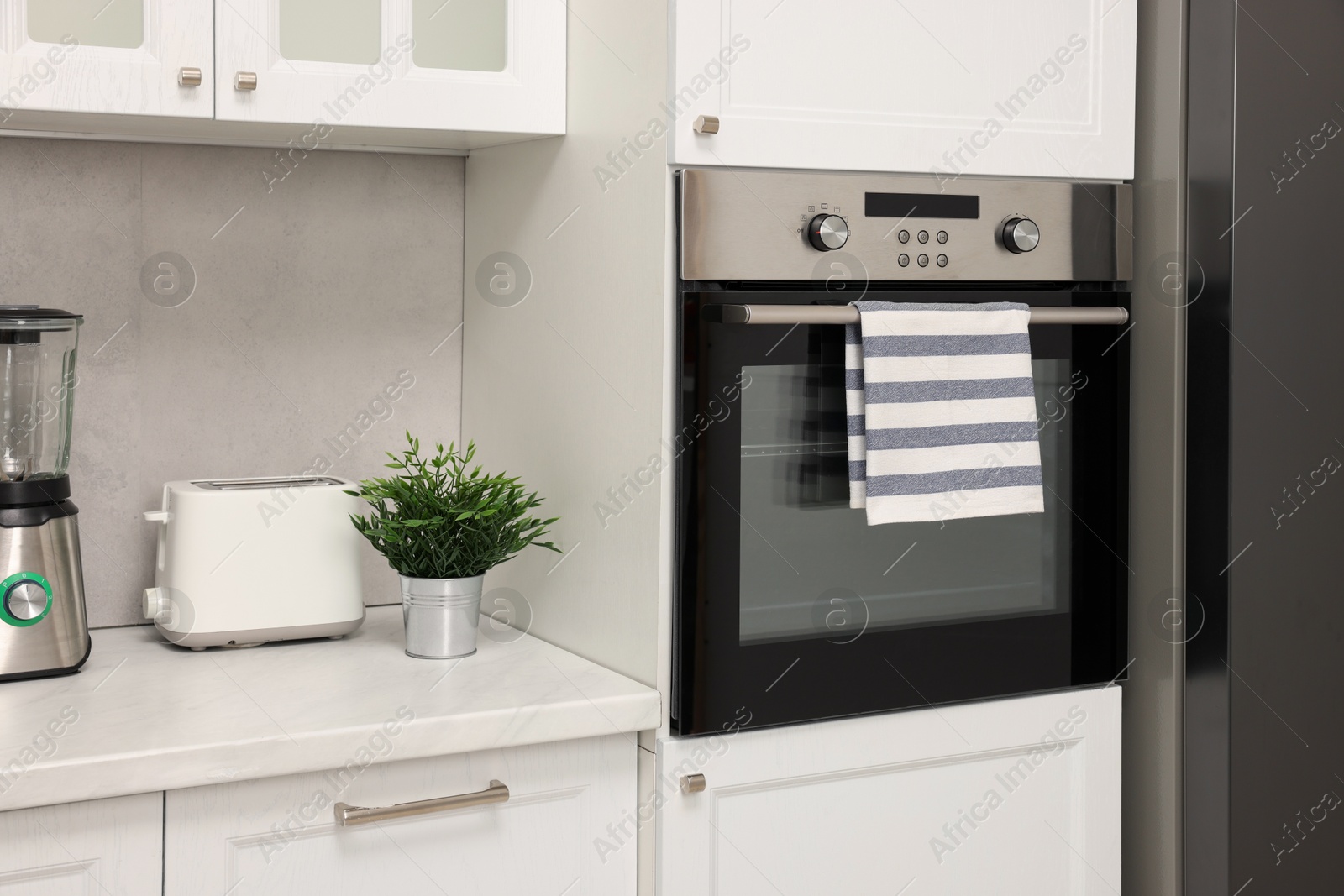 Photo of Electric oven with striped towel in kitchen. Cooking appliance