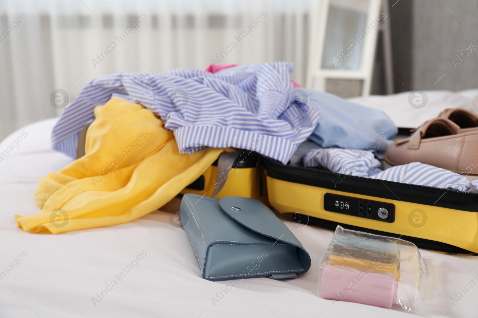 Photo of Open suitcase with traveler's belongings on bed