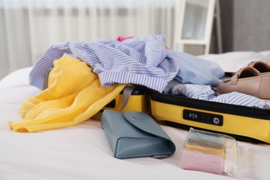 Open suitcase with traveler's belongings on bed