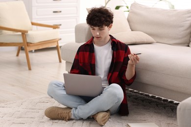 Photo of Teenager with pencil working on laptop at home. Remote job