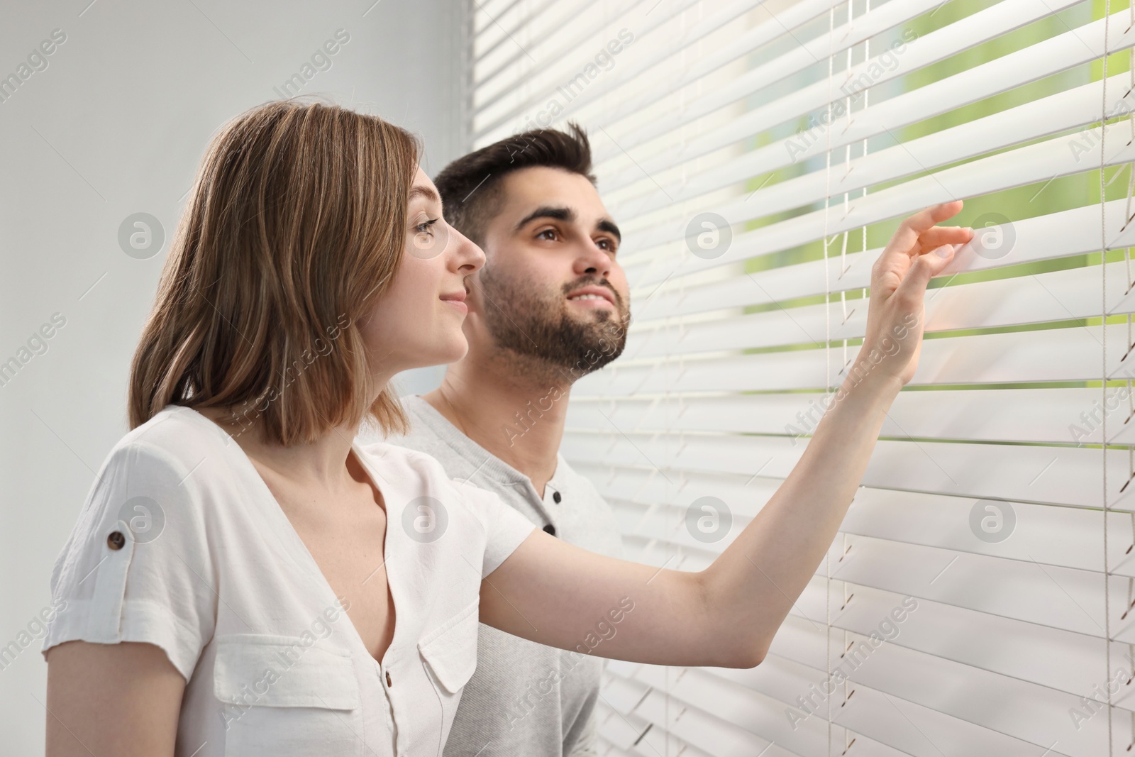 Photo of Young couple near window blinds at home