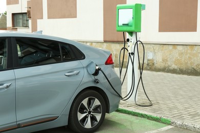 Modern electric car charging from station outdoors