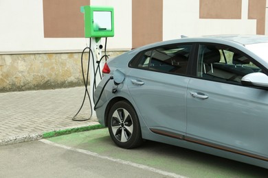 Modern electric car charging from station outdoors