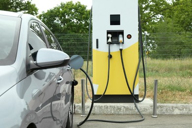 Modern electric car charging from station outdoors