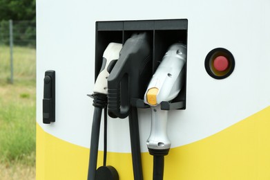 Photo of Modern electric vehicle charging station with plugs outdoors