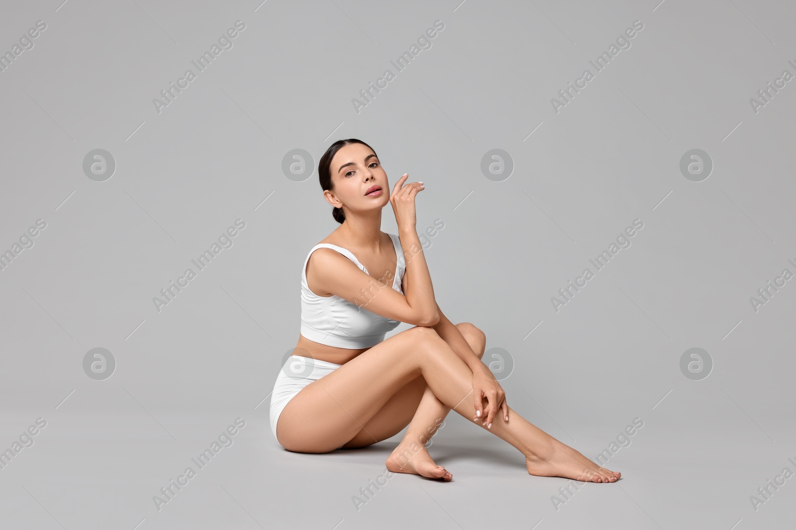 Photo of Beautiful woman with perfect skin in underwear on grey background. Body care