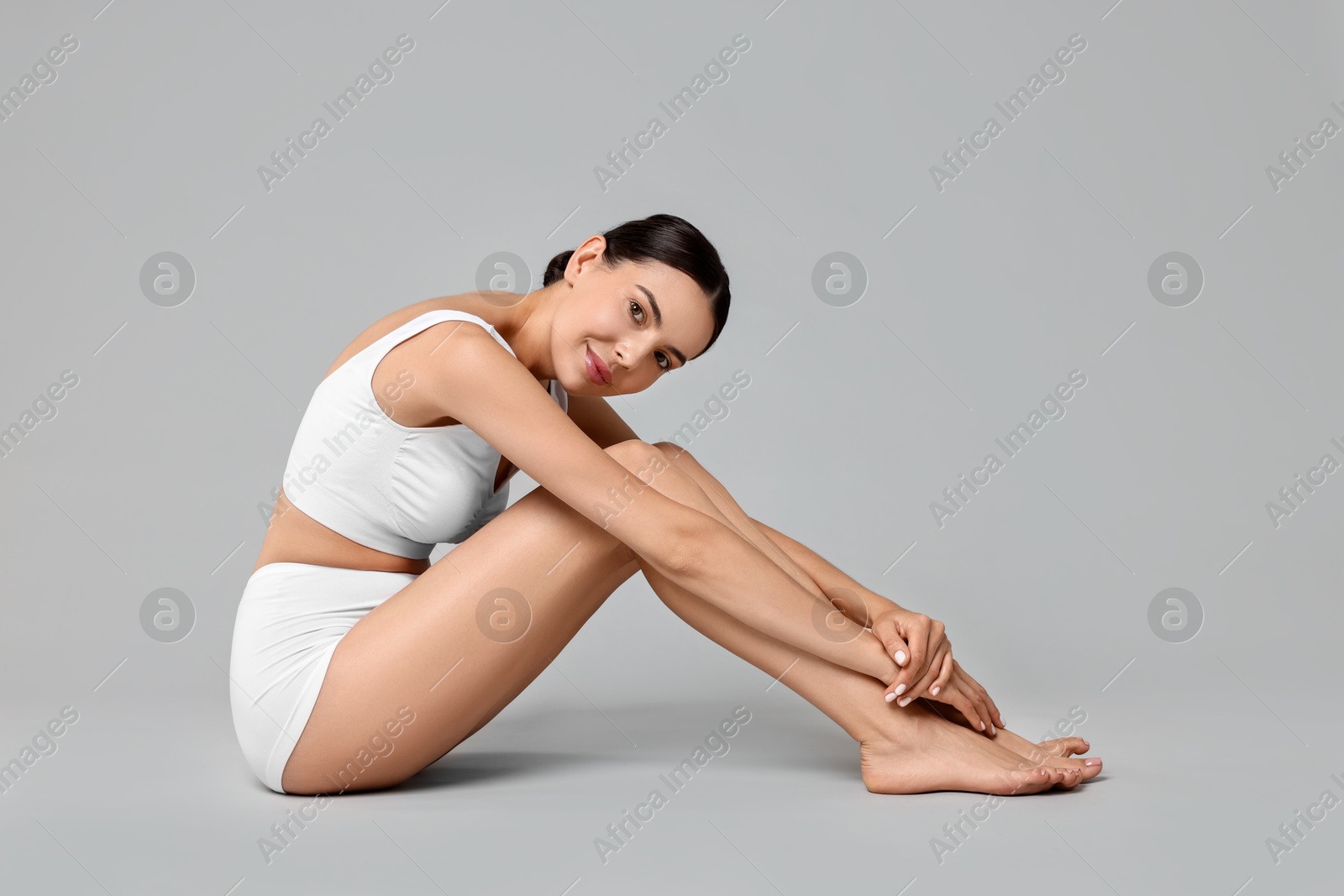 Photo of Beautiful woman with perfect skin in underwear on grey background. Body care