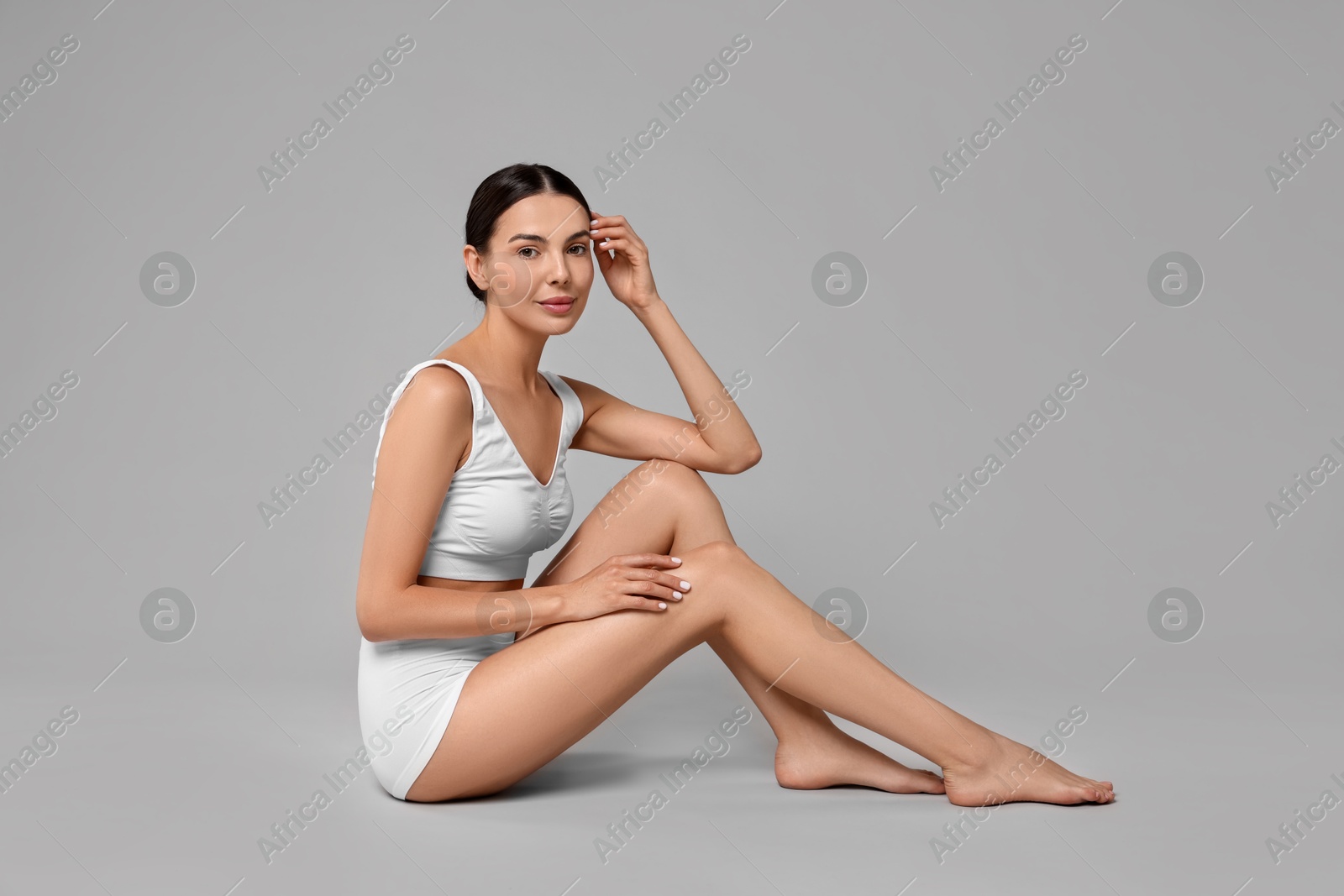 Photo of Beautiful woman with perfect skin in underwear on grey background. Body care