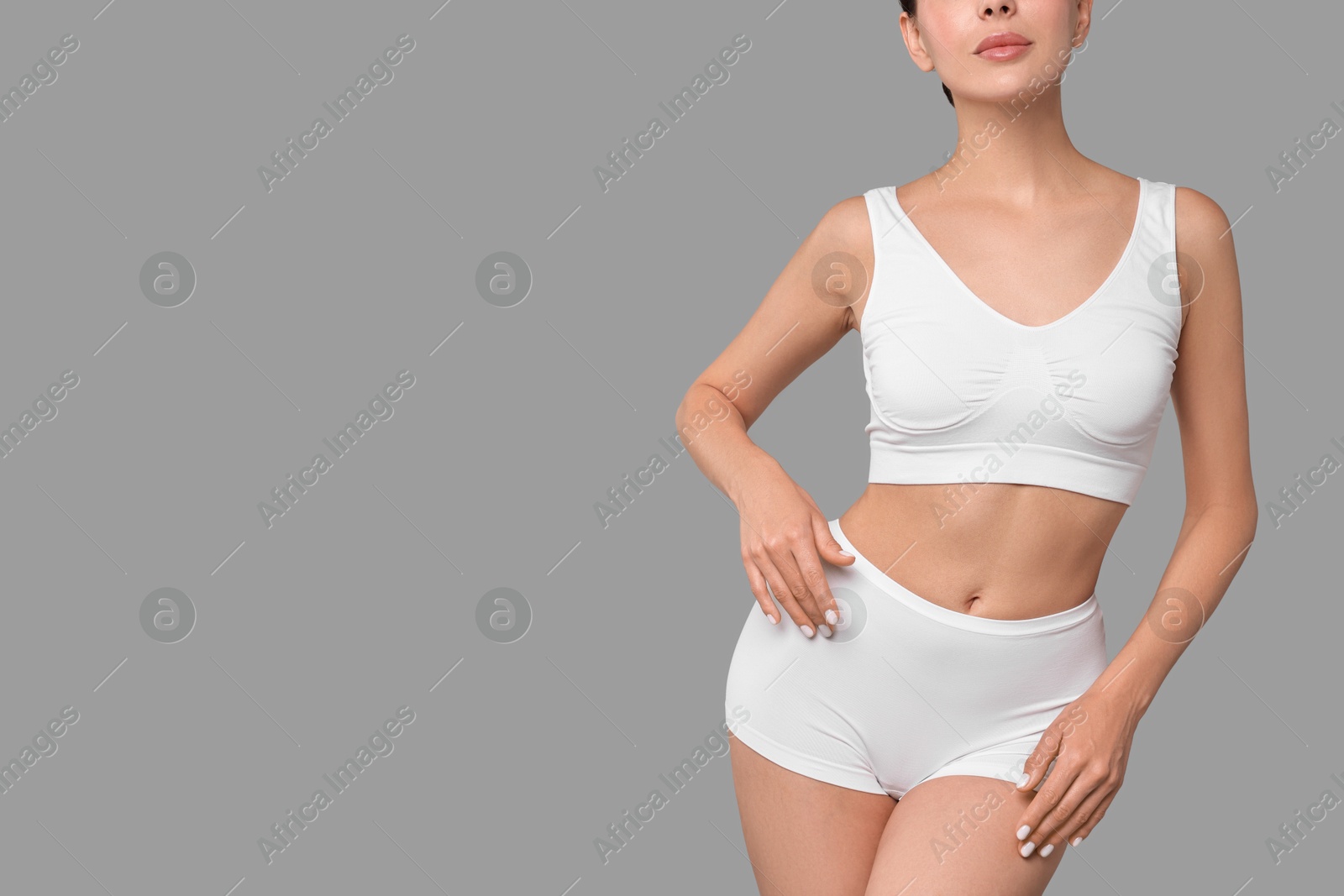 Photo of Slim woman with perfect skin in underwear on grey background, closeup with space for text. Body care