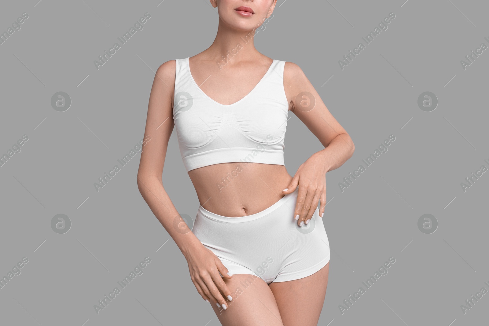 Photo of Slim woman with perfect skin in underwear on grey background, closeup. Body care